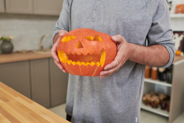 Man Holds Pumpkin for Halloween with Carved Muzzle